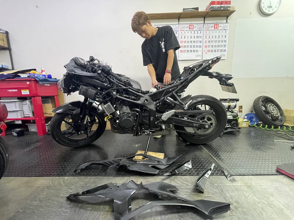バイクを整備しながらカウルやパーツを組み付けしている様子